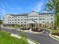 Active Adult Community with an exterior view of an apartment building with a courtyard and benches