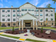 Active Adult Community with an exterior view of an apartment building with a courtyard and benches