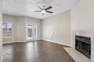 A spacious living room with a fireplace and a ceiling fan.