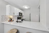 A kitchen with white cabinets and a marble countertop.