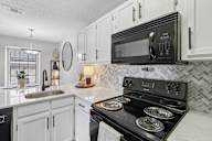 A black microwave is on top of a black stove.