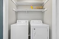 Two white washing machines in a small laundry room.
