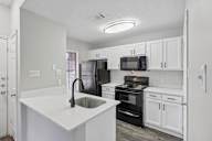 A kitchen with black appliances and white cabinets.