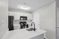 A kitchen with white cabinets and a black stove top.