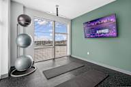 A room with a television on the wall and yoga mats on the floor.