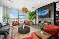 A modern living room with a grey couch, red chairs, and a fireplace.