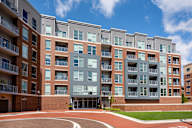 A large multi-story apartment building with a red brick base and grey upper floors.