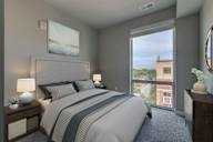 A bedroom with a large bed and a view of a building outside the window.