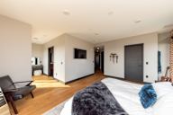 A bedroom with a large bed and a chair.