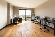 A room with wooden floors and a desk with a chair.