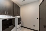 A laundry room with two washing machines and wooden cabinets.
