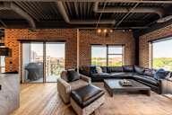 A modern living room with a brick wall and wooden floors.
