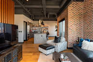 A modern living room with a brick wall and a kitchen area in the background.