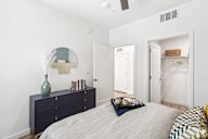 A bedroom with a bed, dresser, and a mirror.