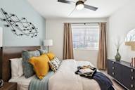 A bedroom with a bed, a ceiling fan, and a nightstand.