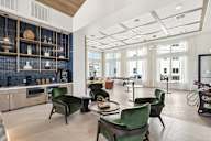 A modern kitchen with green chairs and a blue backsplash.