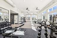 A spacious gym with a variety of equipment and mirrors on the wall.