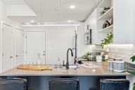 A modern kitchen with a stainless steel sink and black chairs.