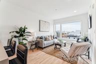 A living room with a couch, chairs, and a potted plant.