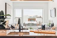 A modern kitchen with a wooden table and a large window overlooking the city.