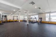 A spacious gym with various exercise equipment and a large mirror on the wall.