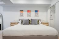 a bedroom with a large bed and three paintings on the wall