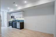an empty room with a kitchen and a hard wood floor