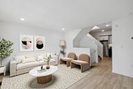 Cozy living area with a beige sofa, chic armchairs, a round marble coffee table, and modern wall art creating a welcoming ambiance.