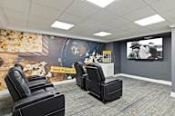 A room with a wall mural and a row of black chairs.