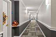 A hallway with a grey carpet and white walls.