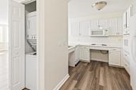 A white kitchen with wood floors and white appliances.
