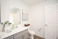 A white bathroom with a toilet, sink, and mirror.