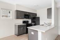 A kitchen with black cabinets and a white counter.