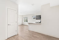 A white door is open to a room with wood flooring and white walls.
