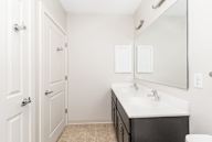 A white bathroom with a sink, mirror, and toilet.
