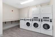 A laundry room with three washing machines and a bench.