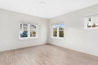 A room with two windows and wooden flooring.