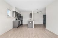 A kitchen with a white counter and a grey fridge.