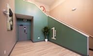 A hallway with a green wall and a plant on the floor at Hudson Heights Apartments, Mechanicville, NY