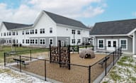 A playground area with a slide and a ball pit in front of a white building at Hudson Heights Apartments, Mechanicville, NY