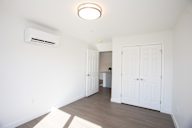 A white room with a ceiling light and an air conditioner unit on the wall.