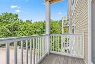 A balcony with a white railing and a view of a green forest.