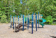 A playground with a green slide and a blue and white structure.