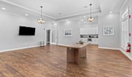 A modern living room with a wooden floor and a television mounted on the wall.