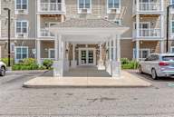 A white covered walkway leads to a building with a white entrance.