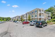 A parking lot with cars and apartment buildings in the background.