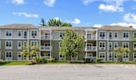 A large apartment complex with a parking lot in front.