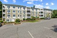 A parking lot in front of a multi-story apartment building.