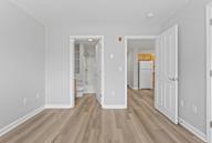 A white room with wood flooring and a doorway leading to another room.