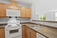 A kitchen with a white stove, a white microwave, and wooden cabinets.